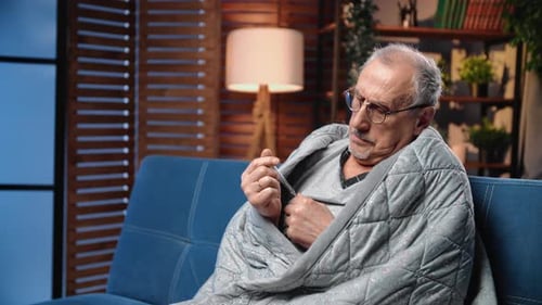 Man with Cold Measuring Temperature on Couch