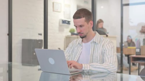 Creative Young Man with Thumbs Up while Working in Office