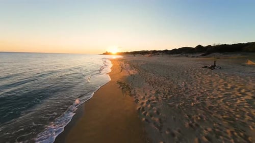 Golden Sunset Over Sandy Beach Shoreline With Gentle Ocean Waves