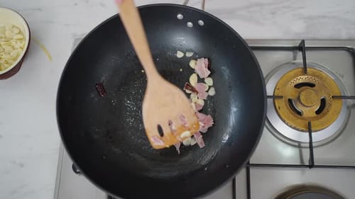 Chopped Ham and Garlic being stirred in Wok