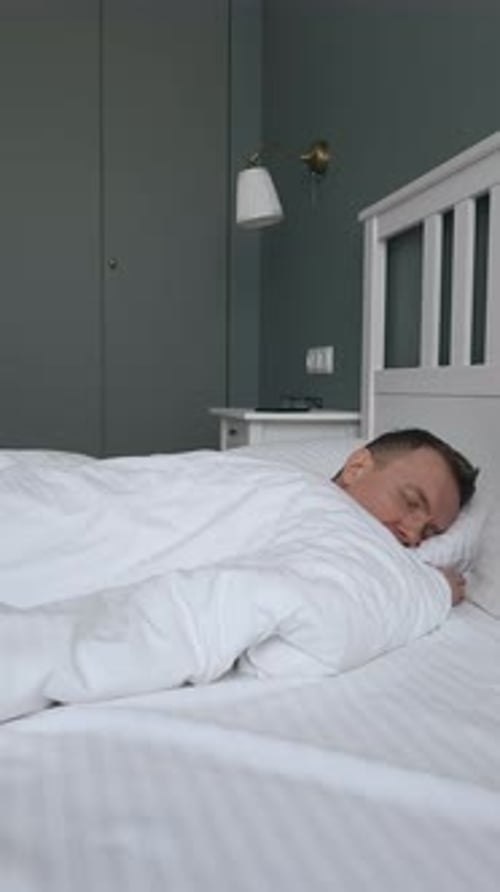 Man Sleeping Soundly Under White Blanket in Bed