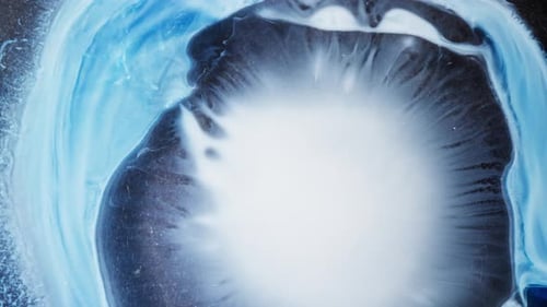 abstract shot of blue and white alcoholic ink swirling and spreading in water