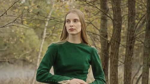 Model posing in green dress in autumn forest