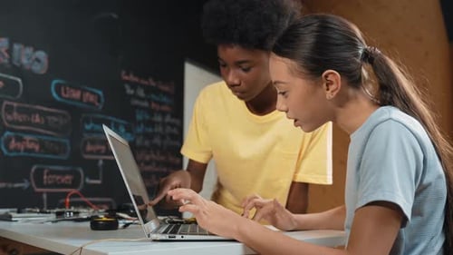 African boy point at laptop screen while cute girl type laptop. Edification
