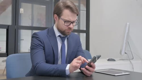 Professional Man Using Cellphone in Modern Office