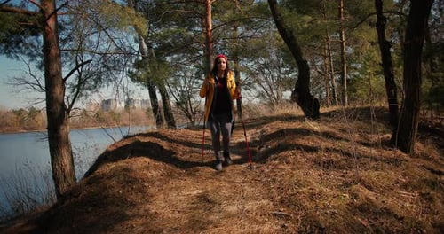Backpacker Hiker Girl with Hiking Poles Walking Between Trees in a Mountain Forest Hispanic Teenager