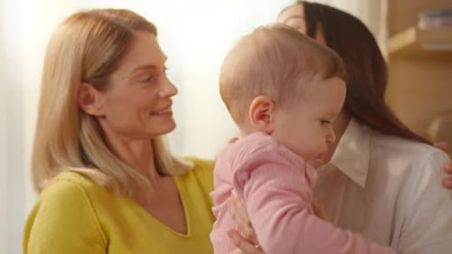 Loving Women Holding Infant Indoors