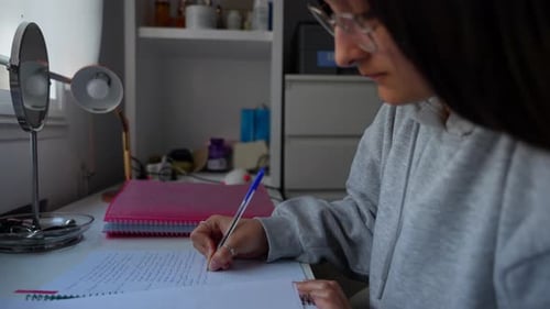 Female Student Writing at Desk Indoors