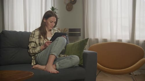 Woman Using Tablet on Couch in Living Room