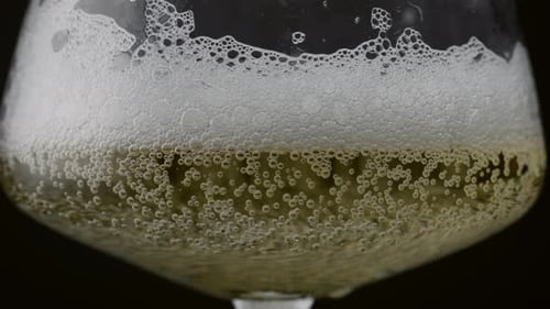 Burbujas de vino espumoso que se elevan sobre líquido sobre fondo negro de cerca