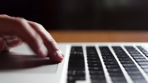 Junger Mann arbeitet beim Tippen auf einer Laptoptastatur, Nahaufnahme