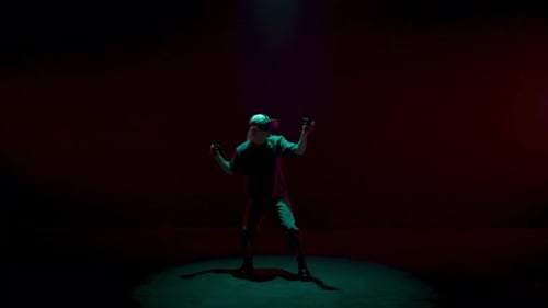 Man With VR Headset and Controllers in Dark Room