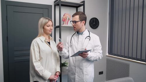 Consultation of the ENT doctor with the patient. Male doctor with an inhaler for asthmatics