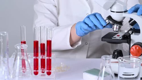 Scientist Analyzing Blood Sample Under Microscope in Lab