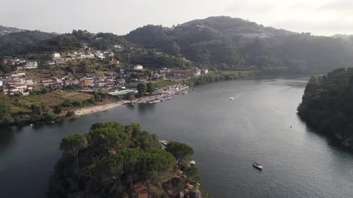 Aerial flying forward Douro river passing by small island, Ilha dos amores - Portugal
