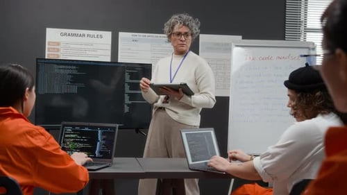 Mature Female Teacher Giving Lesson on Software Development to Inmates in Prison