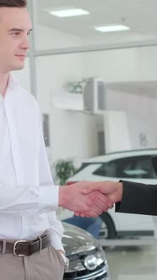 A Man in a Dress Shirt is Discussing Vehicles with a Woman and a Man in a Showroom Vertical Video