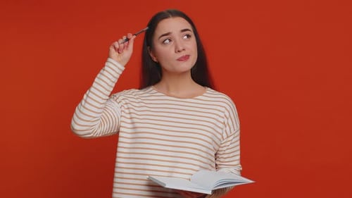 Woman with Notebook Thinking and Writing on Orange Background