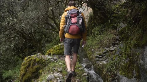 Male Backpacker Trekking On Rocky Hiking Trail With Stream Flowing In Huaraz, Peru. static