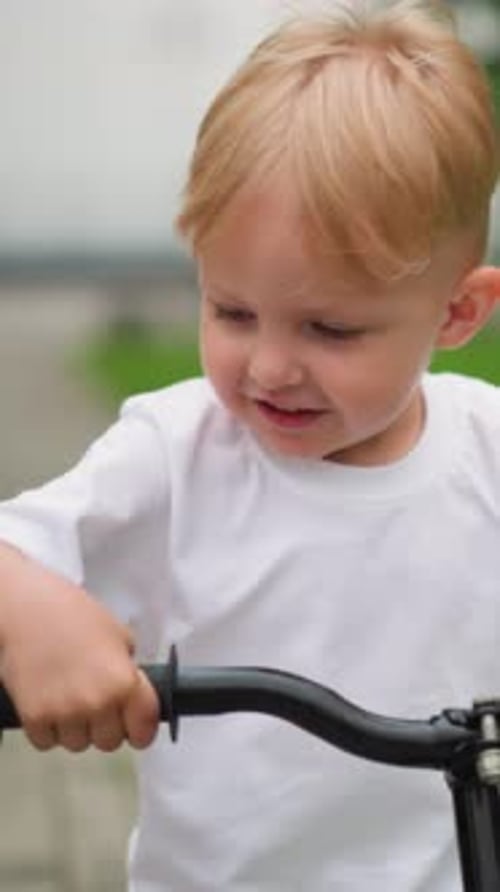Joyful Little Boy Riding Bicycle Outdoors in a Green Park