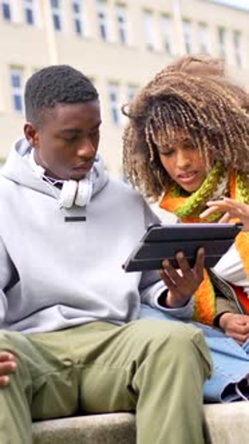 Multiethnic College Students Sitting Outdoors and Using Digital Tablet