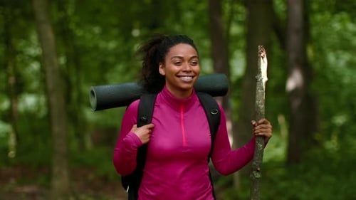 Hiking Woman With Yoga Mat in a Green Forest During a Sunny Day