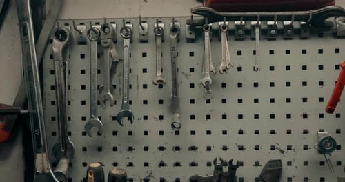 Hand Selecting Wrenches From an Organized Tool Wall in a Workshop