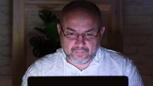 Man Looking Intently at Computer Screen at Night