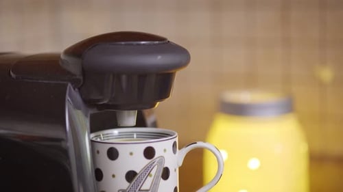 Close up of a pod coffee A hand opens and loads a coffee pod into the turning the on. Coffee pours i