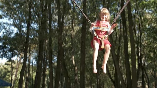 Child Girl Jumping Fastened on a Trampoline in Summer Park