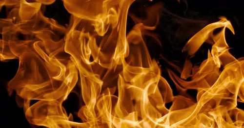 Lebendige Nahaufnahme wirbelnder orangefarbener Feuerflammen vor einem dunkelschwarzen Hintergrund, die Dynamik einfangen