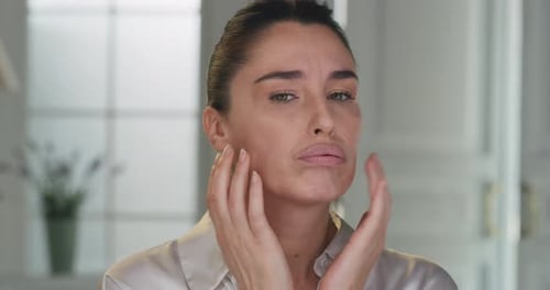 Woman Giving Herself a Facial Massage in Bathroom