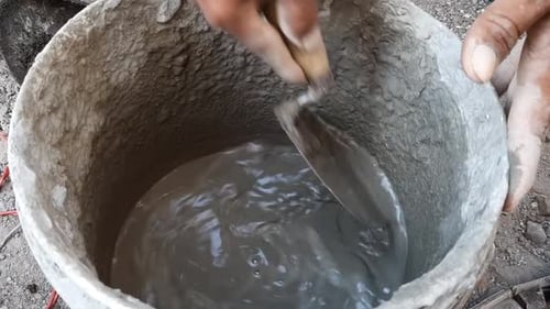 Man Mixing Cement in Bucket with Trowel