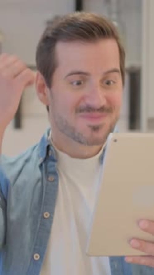 Excited Man Celebrates News on Tablet Indoors