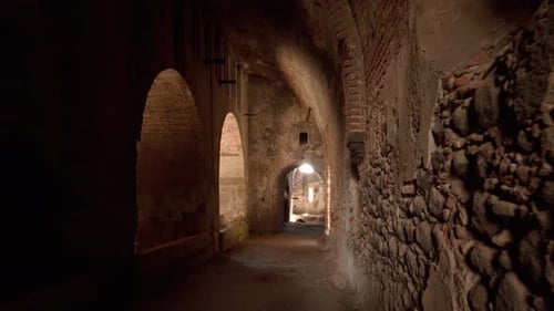 Walking POV through ancient stone corridor with arches and light at end