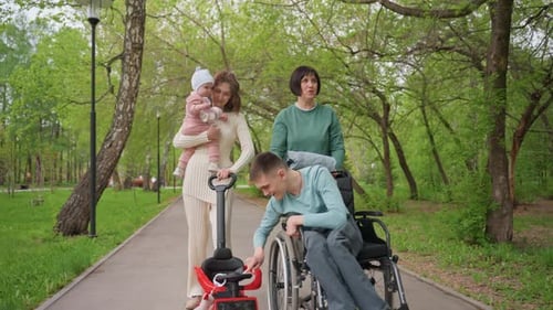 Family Enjoying Walk Group Of Women And Man With Wheelchair And Infant Caucasian Family Including