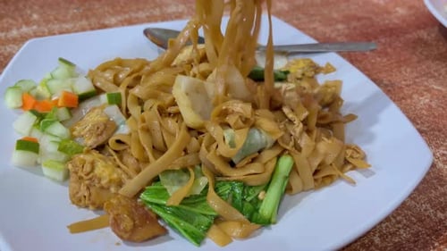 Eating kwetiau with chicken and eggs. Fried kwetiau is a Chinese food.