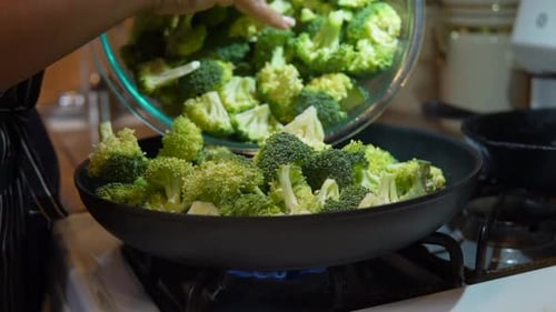 Filling a skillet with freshly cut broccoli to cook, fry or steam - slow motion