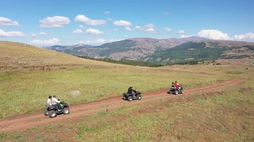 Aerial View Of Group Of People Riding On All Terrain Quadricycle Vehicle Along Mountain Road