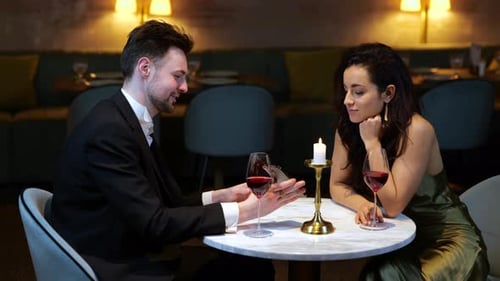 Happy Man Showing Smartphone for His Girlfriend While Having Romantic Date in the Restaurant