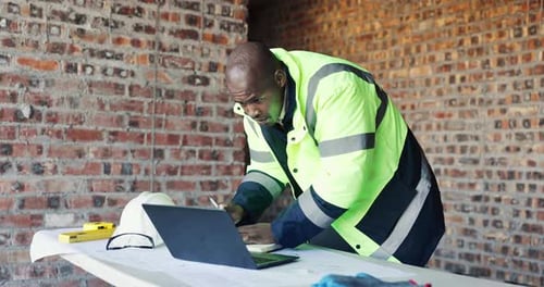 Typing, review or black man with laptop at construction site, renovation planning or budget update