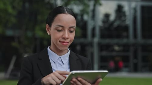 Young Woman Uses Tablet Outdoors Near Office Building