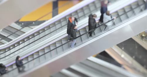 People in motion in escalators at the modern shopping mall. Tilt shift lens shooting with super