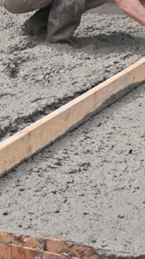 In Construction Site Mason Levels Screeding Concrete for a Foundation