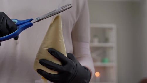 Woman Opens Pastry Bag with Scissors