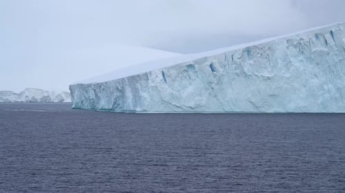 Incrível iceberg grande da Antártica navegando com montanhas cobertas de neve ao fundo. Alta qualidade