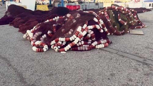 Stack pile of fishing nets and tackle, large stack lying on asphalt surface outdoors at warehouse, f