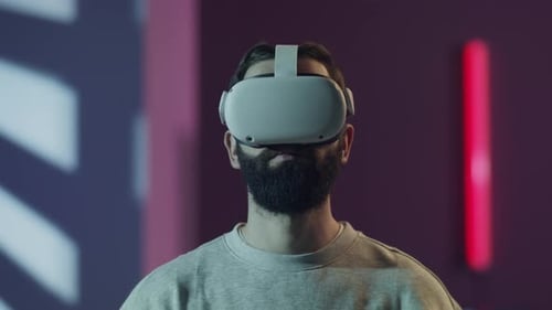 Bearded Man Wearing a VR Headset Looks Around in a Futuristic Room