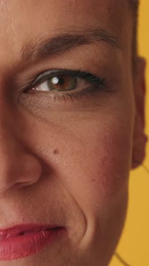 Detailed close-up shot half of a woman's face isolated on yellow background