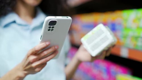 close up hand woman customer checking product information at mobile phone in supermarket Female Shop